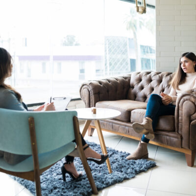 Woman sharing problems with female therapist while sitting on couch at office